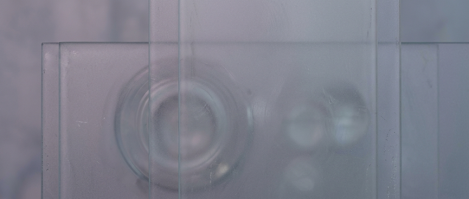 Frosted glass texture with faint circular reflections in muted gray-blue tones, evoking the quiet stall of a technology caught between promise and reality.